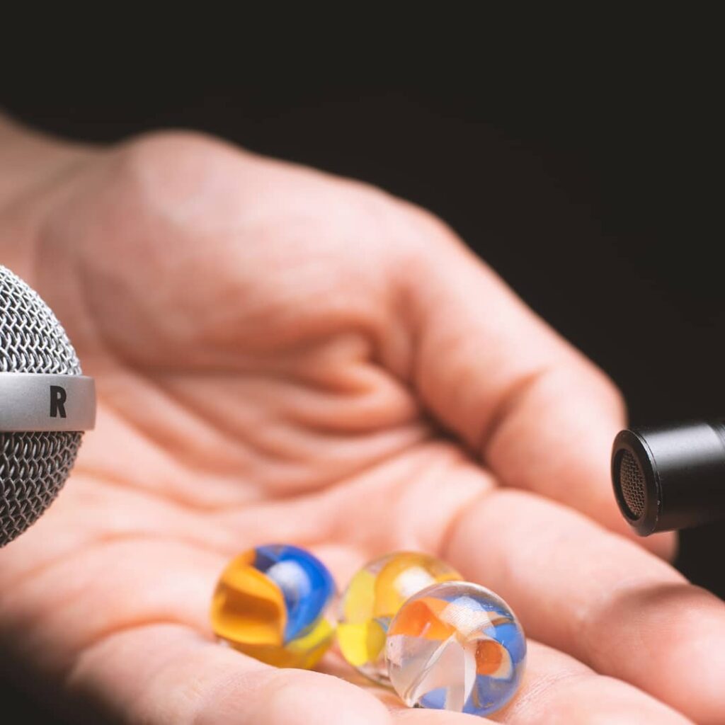 Open hand holding multiple marbles next to two microphones